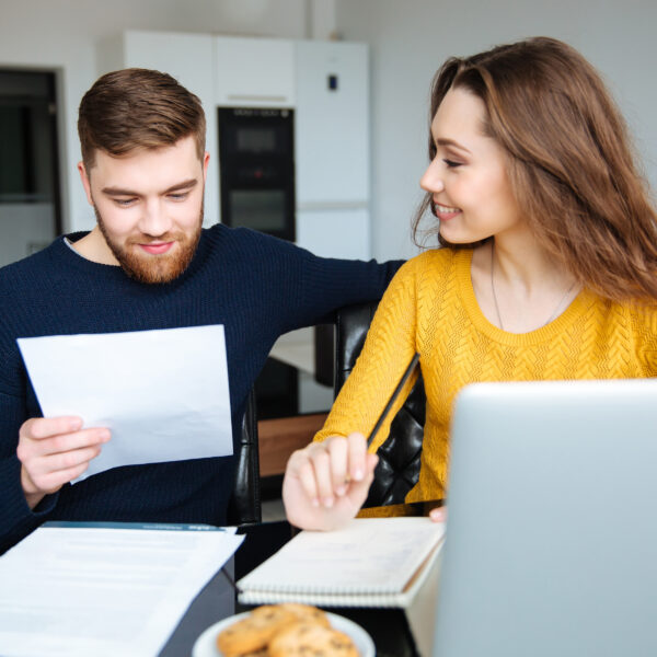 Happy,Young,Couple,Calculating,Bills,At,Home